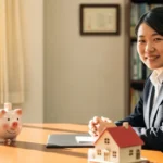 安定した将来設計をイメージし、家と貯金箱を見つめる公務員の姿。