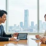 横浜のみなとみらいを背景に資産運用の相談をするカップルと専門家